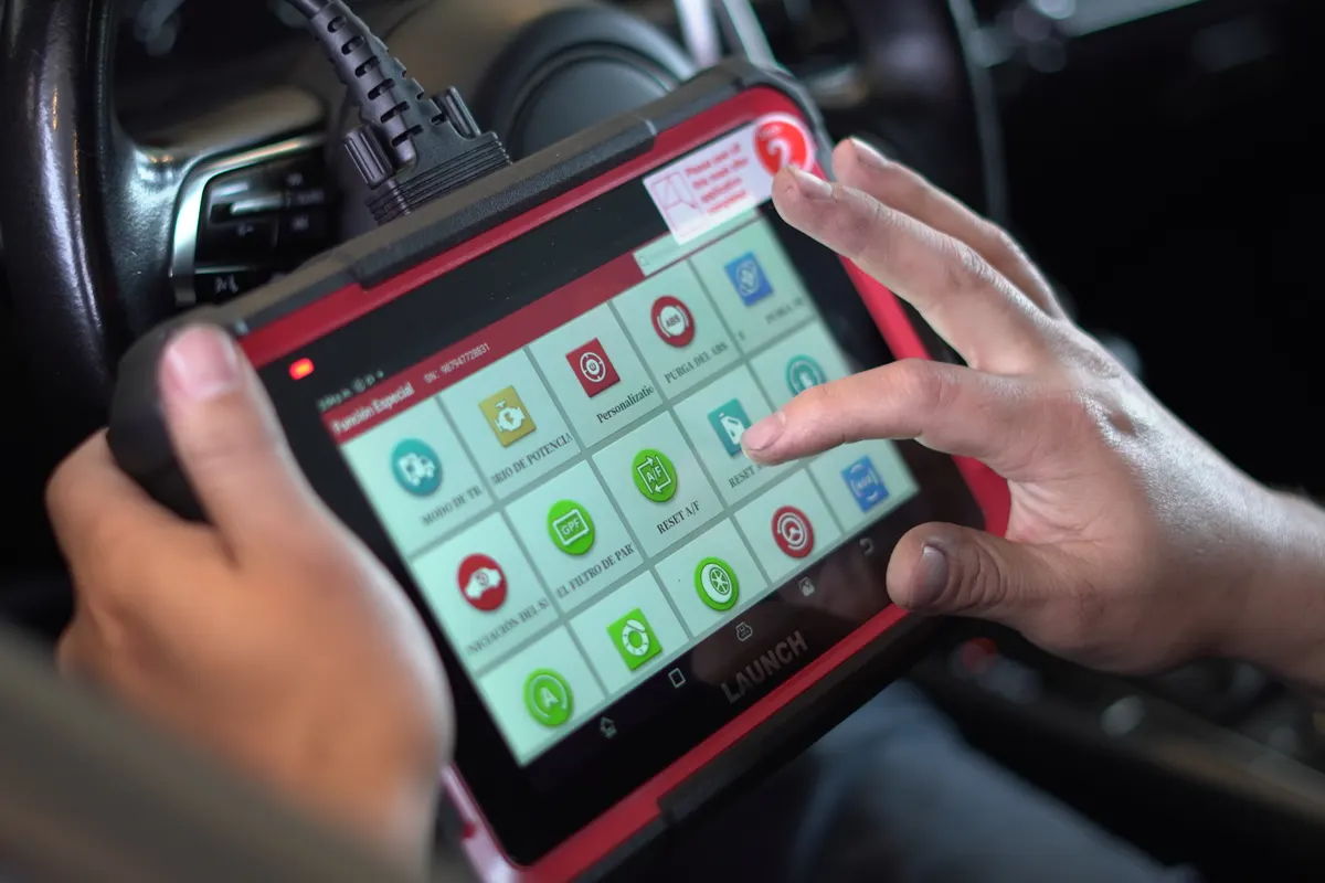 Escáner de diagnóstico multimarca conectado a un auto durante una revisión a domicilio