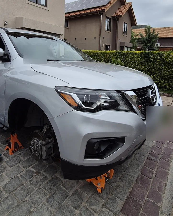 Nissan Pathfinder con una rueda desmontada en el estacionamiento de una casa de condominio