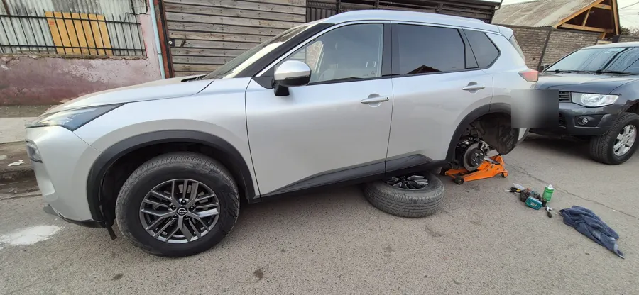Nissan X-Trail con una rueda desmontada para el cambio de frenos en la calle